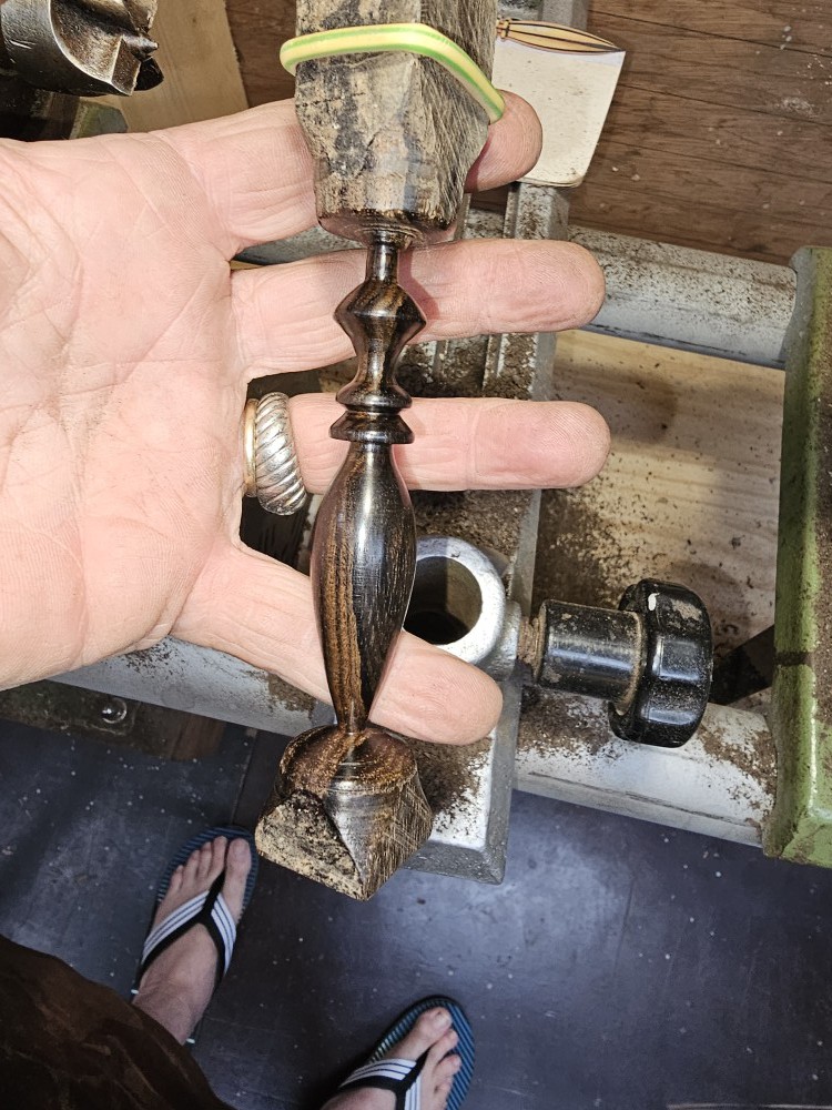 Pendule en bois présenté dans la main avant sa séparation du bois